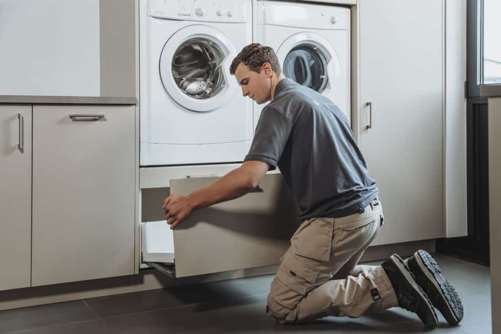Man die een lade in een wasmachinekast monteert