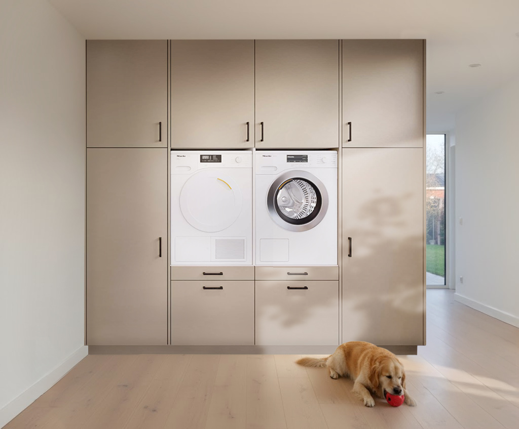 Moderne wasruimte met ingebouwde Miele wasmachine en droger in beige kastenwand, met een gouden retriever die op een rode bal kauwt op de houten vloer.